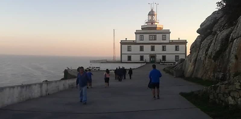 a picture of a group of pilgrims walking to the lighthouse on the Camino