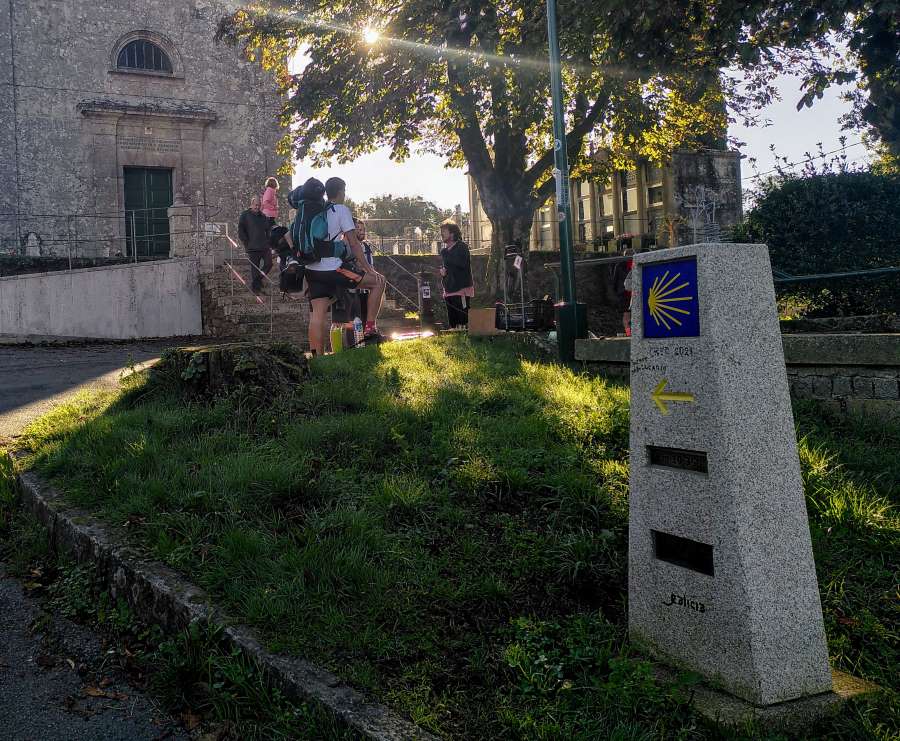. A group of pilgrims is standing in front of the cathedral on the Camino