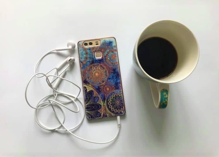 phone playing podcast with headphones and coffee
