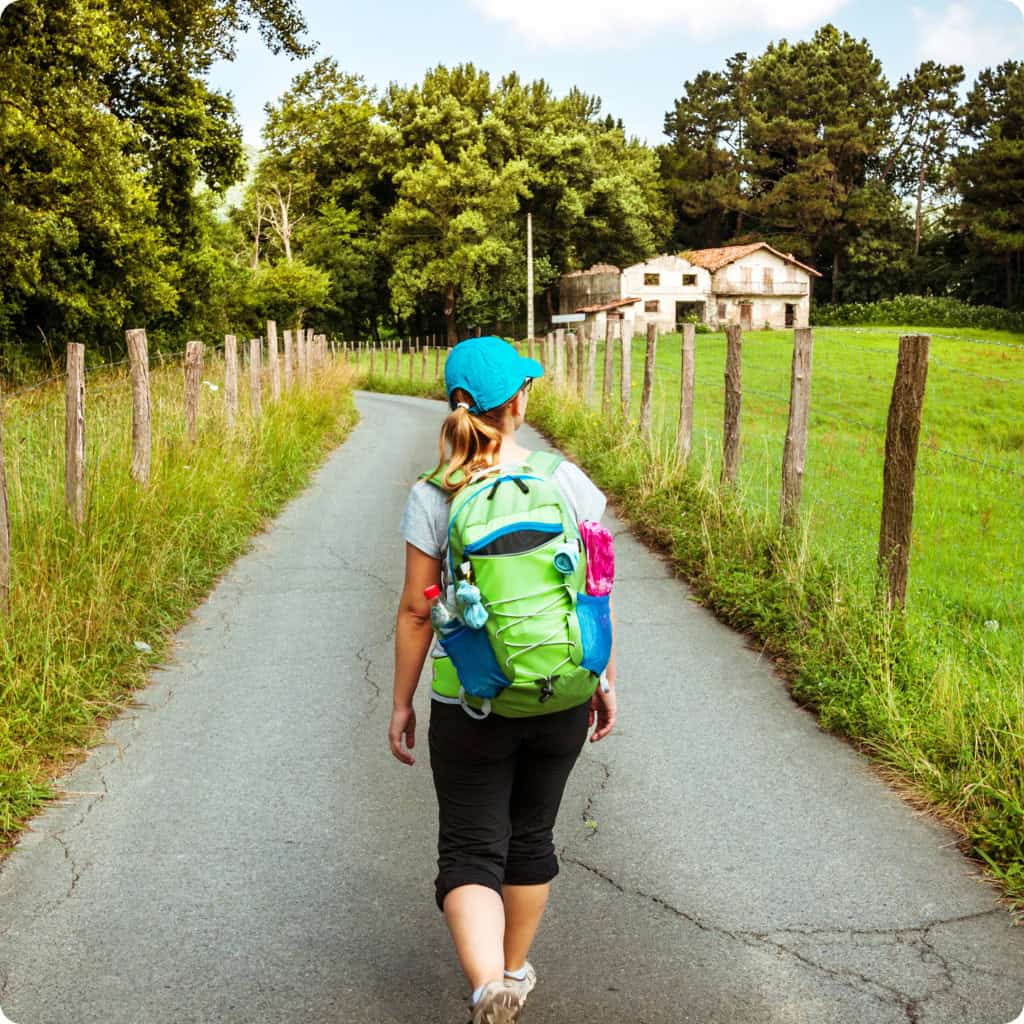 Girl walking camino path with bag pack