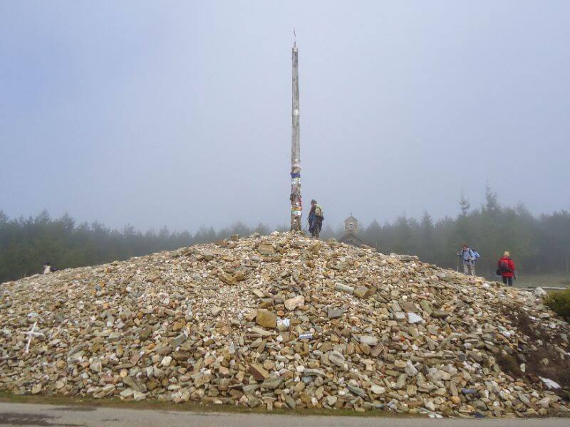 pilgrim dropping stone at cruz de fero on the Camino Frances
