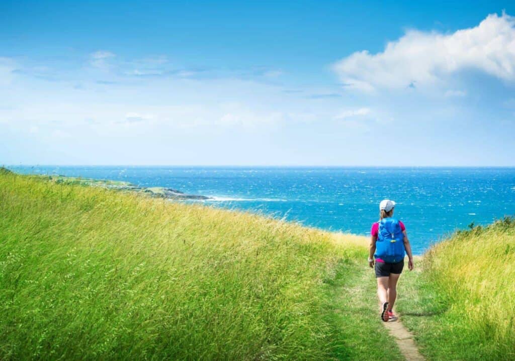 woman walks on the camino del norte towards the sea