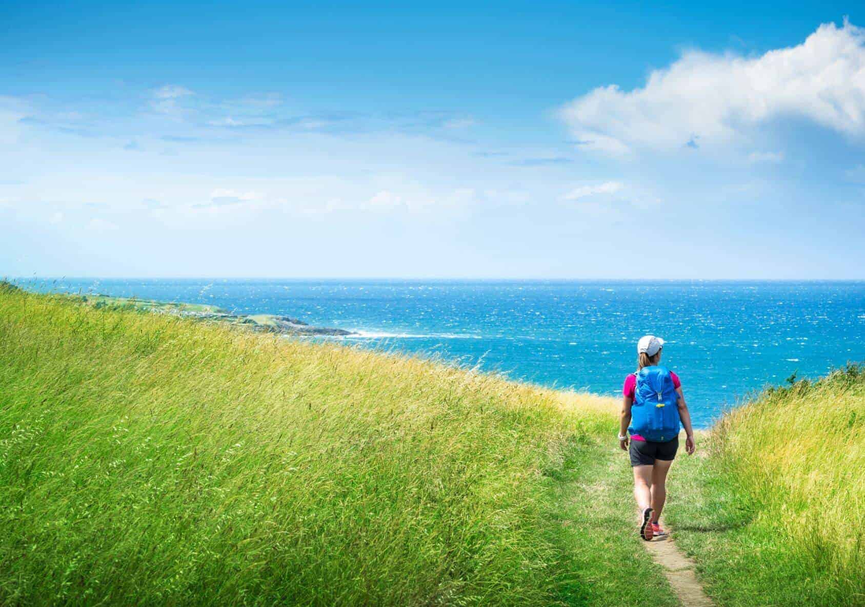woman walks on the camino del norte towards the sea