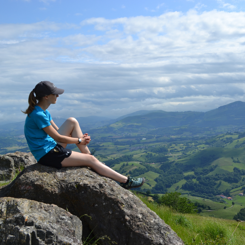 Girl pilgrim sitting on top of pyranees mountain range and taking in the view