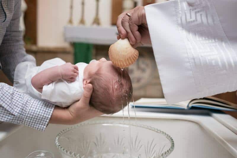 baptism baby baptized priest pouring holy water on babyies head with clam shell in church pentecost sunday