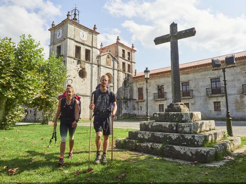 a picture of 2 pilgrims walking in front of a church