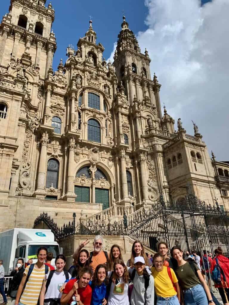 a picture of a group of pilgrims standing in front of a cathedral