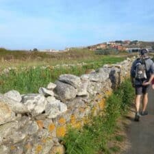 a picture of 2 pilgrims walking alon the coast on the Camino