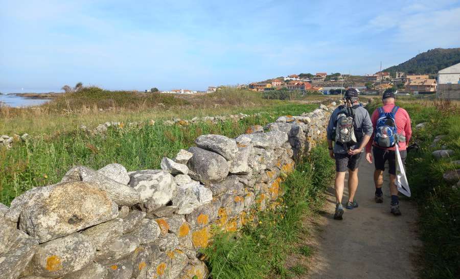 a picture of 2 pilgrims walking alon the coast on the Camino