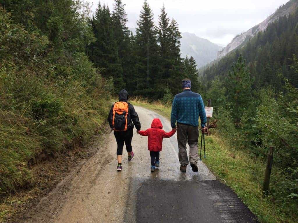 Family walking the Camino through forest in rain