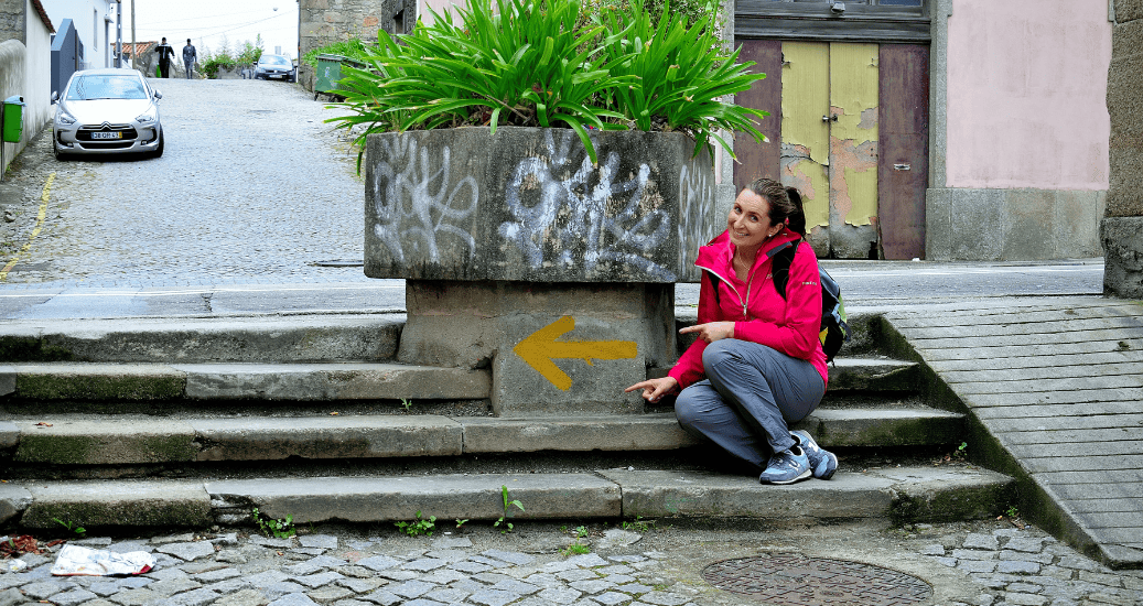 Yellow arrow with girl sitting next to it in porto