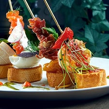 Classic Spanish Antipasto - Pintxos or Tapas with Shrimp, Camembert, Salmon and Jamon in a White Plate. Selective Focus