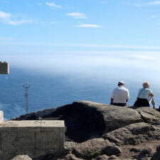 Pilgrims sitting by Fisterra
