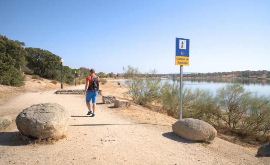 Pilgrim walking by camino de santiago sign