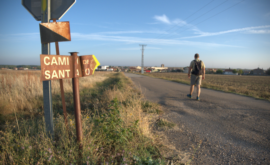 Pilgrim walking by camino de santiago sign