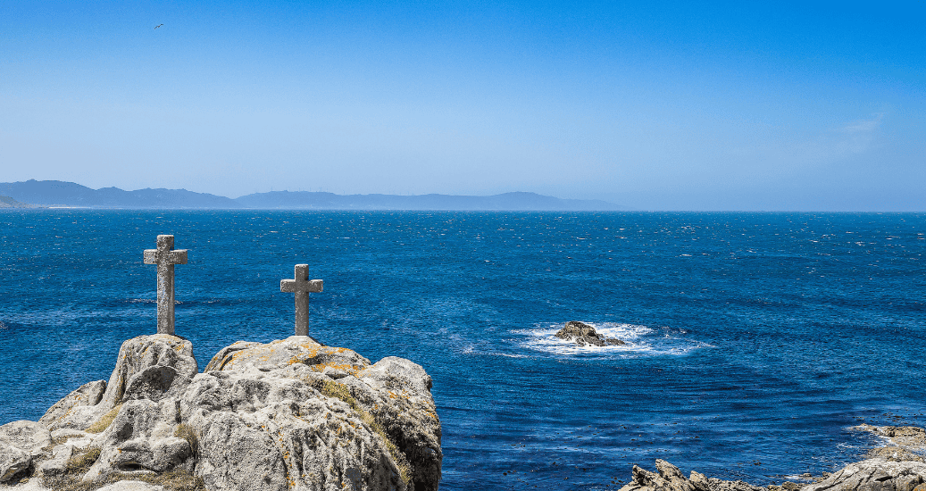 stone crosses on the coast gives death in the foreground and the brave Atlantic ocean in the background at the punta roncudo lighthouse. Lighthouse trail