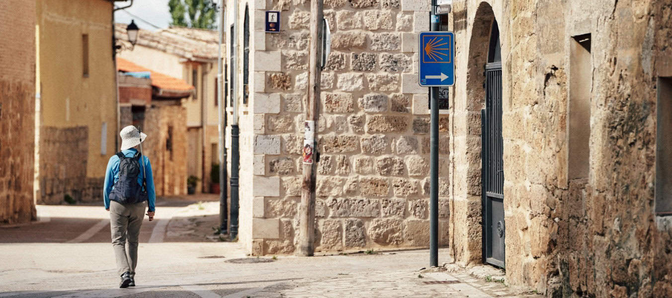 Pilgrim walking in burgos with yellow arrow camino