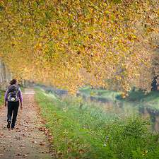 Pilgrim walking by a canal in Autumn